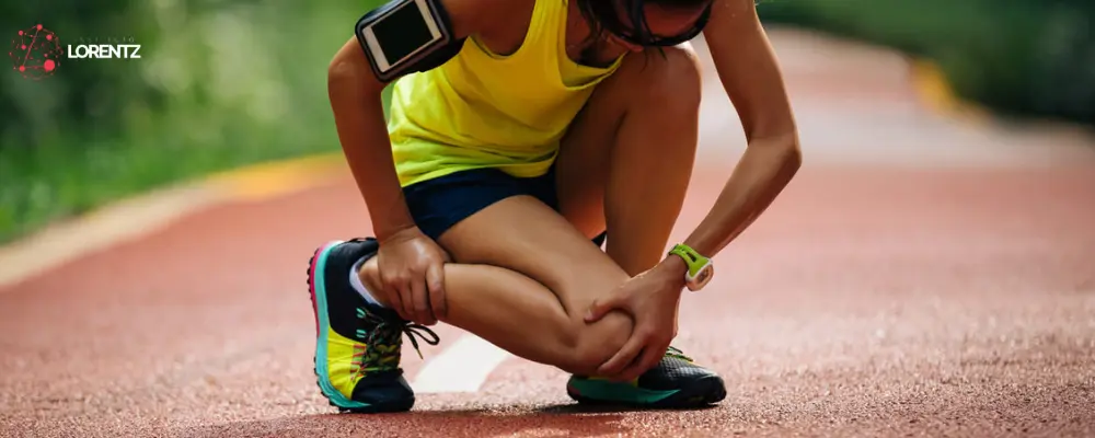 Estratégias Eficientes para Prevenção de Lesões Esportivas 1 Uma atleta com uma camiseta amarela em uma pista de atletismo sentido dor no joelho e no tornozelo